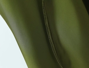 Detailed macro view of the olive green fabric's precise overlock stitching and smooth texture