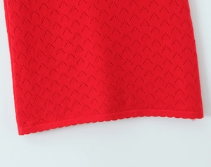 Detail of red knitted dress with geometric hollow texture and scalloped hem edge