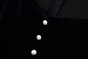 Detail of three pearl buttons on black velvet dress with elegant stitching and zipper