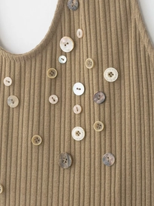 Detail of camel ribbed knit top featuring decorative vintage buttons and fine texture