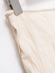 Close-up of beige midi skirt waist featuring invisible zipper and pleated cotton linen fabric