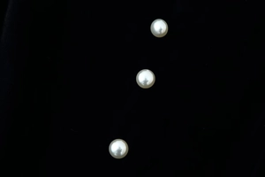 Macro shot of three round white pearls with glossy luster on a stark black background