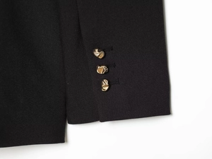 Détail de la manche du blazer noir avec trois boutons décoratifs dorés irréguliers