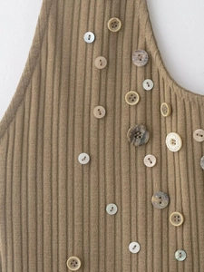 Macro view of khaki ribbed knit fabric featuring decorative assorted designer buttons
