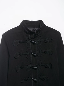 Détail d'une veste noire à col montant avec attaches traditionnelles et boutons en corne