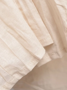 Detailed macro view of beige pleated fabric texture with neat stitching and cotton-linen weave