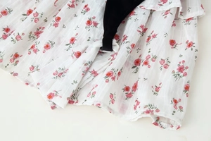 Detail of floral chiffon fabric with pink roses, jacquard stripes, and black velvet trim