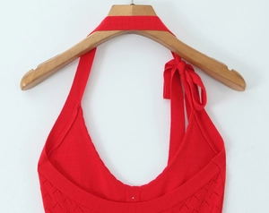 Macro detail of red halter knit dress featuring diamond hollow-out patterns and neckline ties