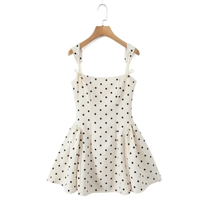 Detail of white polka dot dress featuring elegant bow straps and pleated flared skirt