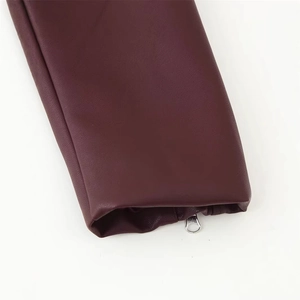 Détail de la manche d'une veste en cuir bordeaux foncé avec fermeture éclair argentée et grain