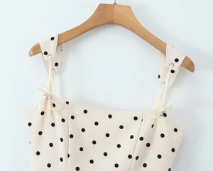 Close-up of beige polka dot dress with tie-up straps and metal eyelet details