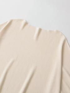 Detailed close-up of cream boat neck knitwear showing smooth fine-knit texture and elegant collar