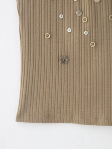 Detail of ribbed knit top showing texture and decorative irregular buttons on fabric