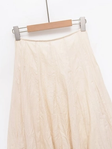 Detail view of beige midi skirt featuring natural crinkle texture and lightweight fabric