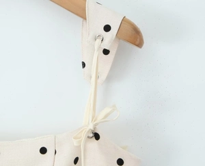 Detail of cream polka dot fabric featuring metal eyelets and adjustable lace-up straps