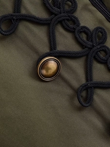 Detailed close-up of military green blazer with vintage brass button and woven cord knot