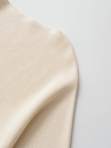 Close-up of off-white fine knit sweater shoulder showing seamless weave and soft texture