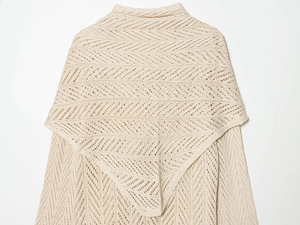 Detailed view of beige pointelle knit texture with geometric patterns on an elegant shawl