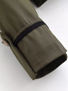 Detail of olive green jacket cuff with black stripes and vintage copper button