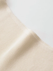 Macro shot of fine mesh knit fabric texture in cream color showing detailed craftsmanship