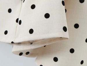Detail of cream fabric with large black polka dots showing high-quality stitching and hem