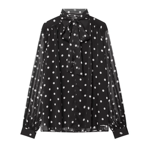 Detailed close-up of a black and white polka dot chiffon shirt with elegant bow tie neck