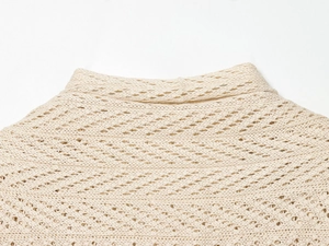 Macro detail of cream knit sweater featuring hollow diamond crochet pattern and ribbed neckline