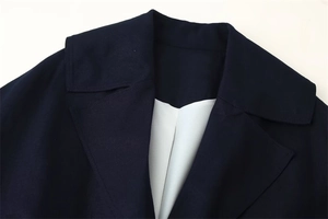 Dettaglio del colletto del cappotto blu navy con cuciture e fodera interna bianca