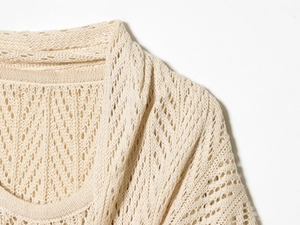 Detailed macro view of the delicate wave-pattern openwork knit texture on this cream cardigan