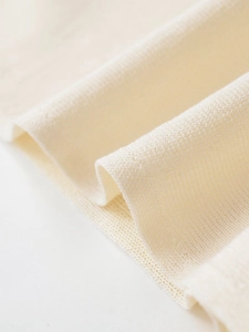 Macro detail of breathable beige knit fabric with soft texture and refined weave