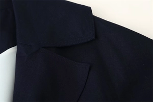 Dettaglio del trench blu navy con bavero classico e trama in tessuto twill raffinato