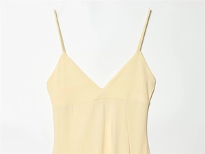 Detail of a cream yellow V-neck dress with slim spaghetti straps and premium stitching