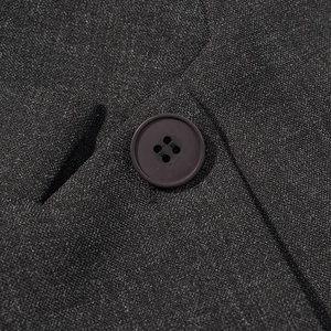 Macro detail of the premium black wool blend fabric and four-hole resin buttons on blazer