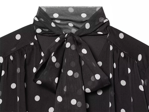 Detail view of a black polka dot chiffon shirt featuring an elegant pussy-bow tie neckline
