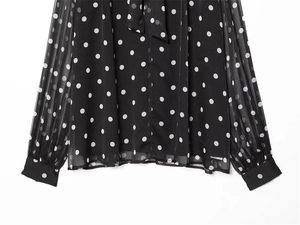 Detailed close-up of long sleeve polka dot chiffon shirt with elegant bow tie neck and cuffs