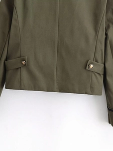 Detail view of military green blazer hem with vintage bronze buttons and decorative straps