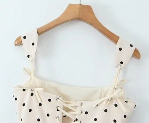 Detailed close-up of lace-up corset front and bow straps on a polka dot dress