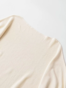 Close-up of cream knit fabric texture on an elegant off-the-shoulder sweater