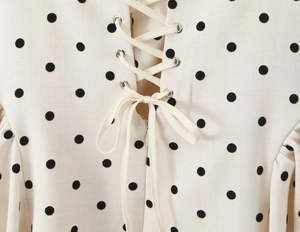 Close-up of lacing detail with silver eyelets on polka dot high waist dress