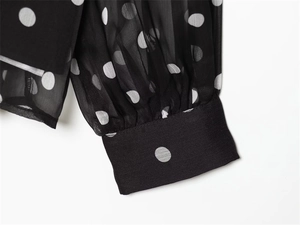 Detail of white polka dot pattern on black chiffon fabric with wide cuff stitching