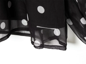 Detail view of lightweight black chiffon fabric with classic white polka dot pattern