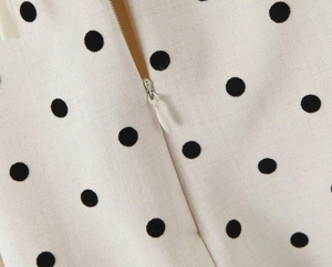 Detail shot of invisible zipper closure on white polka dot dress fabric texture