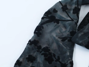 Détail du tissu en maille floquée avec des motifs floraux en velours sur voile noir