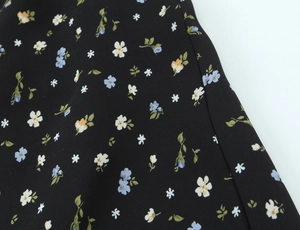 Détail du tissu en mousseline noire avec un motif floral éclatant et des coutures précises