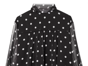 Close-up of semi-sheer black chiffon blouse featuring white polka dots and pleated collar