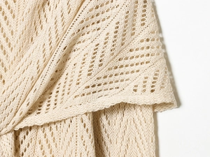 Detailed close-up of beige crochet knit fabric with intricate hollow-out geometric patterns