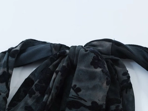 Détail du tissu en maille floquée noire avec motif floral et couches semi-transparentes
