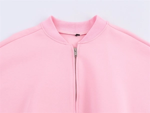 Detail of light pink bomber jacket featuring silver zipper and ribbed knit collar texture