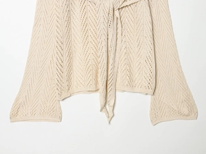 Detail of beige hollow knit cardigan with dot texture, waist tie, and flared sleeves