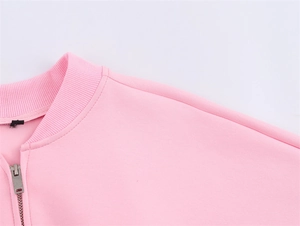 Detail of pink bomber jacket with ribbed collar, drop shoulders and silver metal zipper